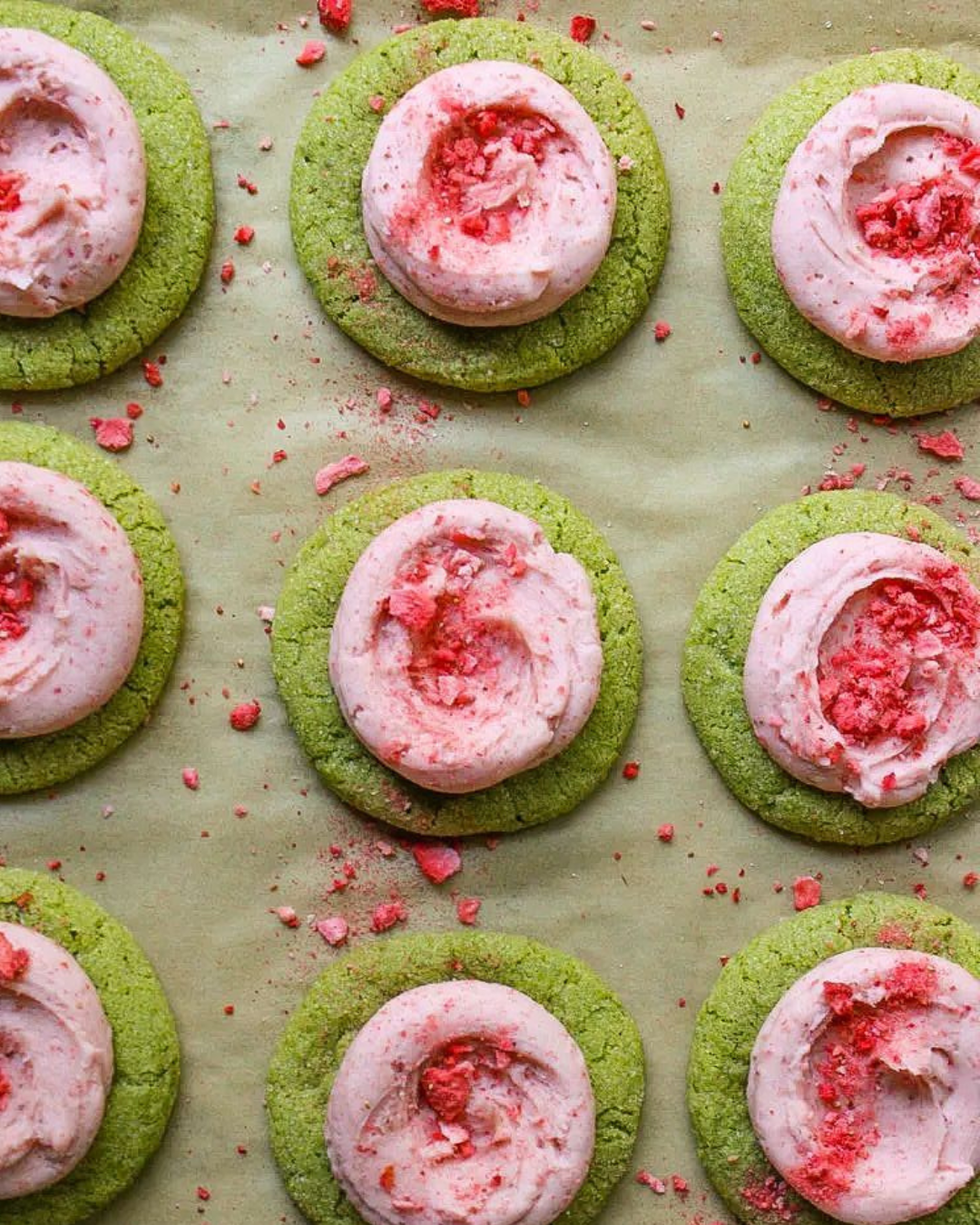 Matchakoekjes met aardbeienfrosting op bakpapier.
