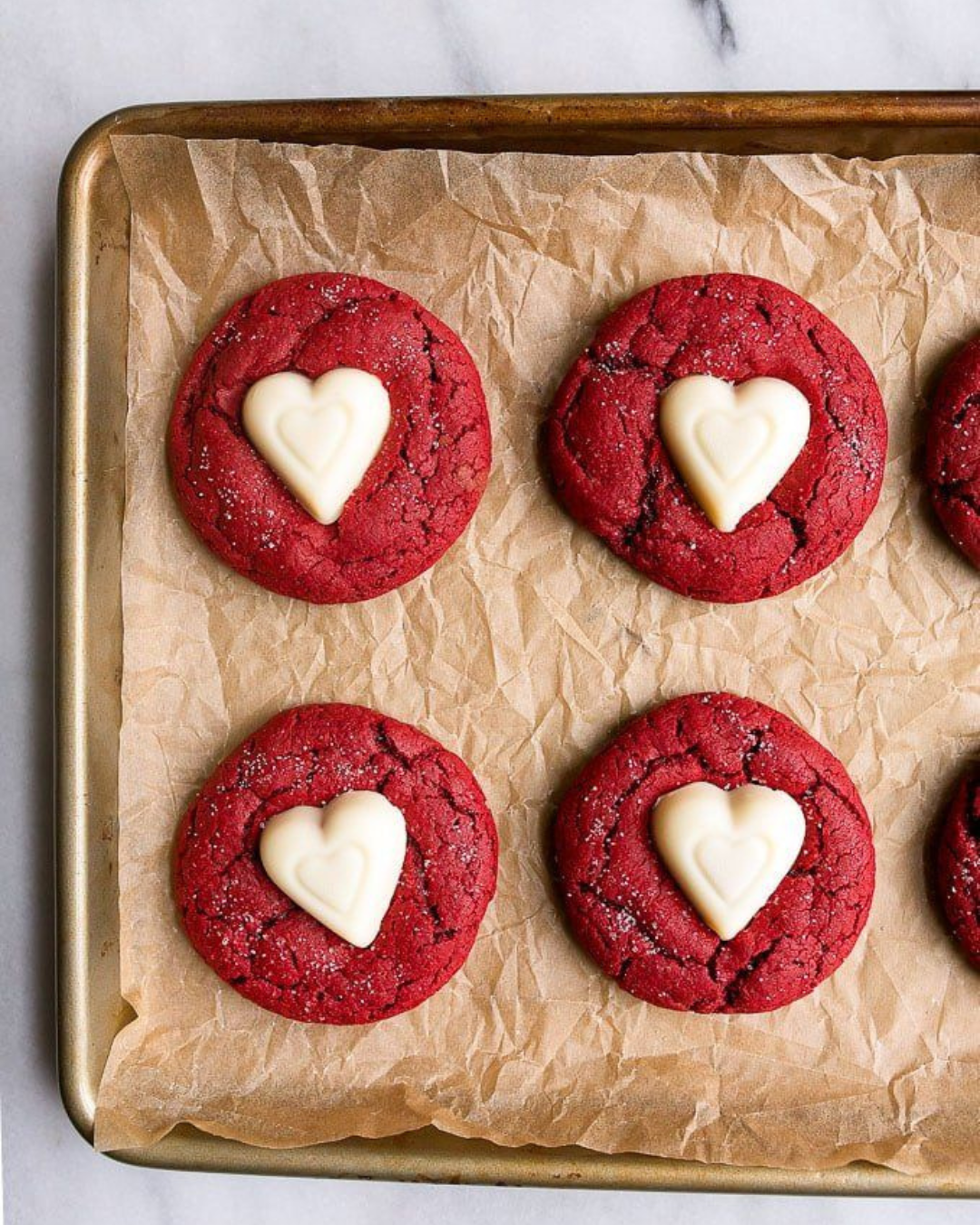 Red velvet koekjes met een chocoladehartje op bakpapier.